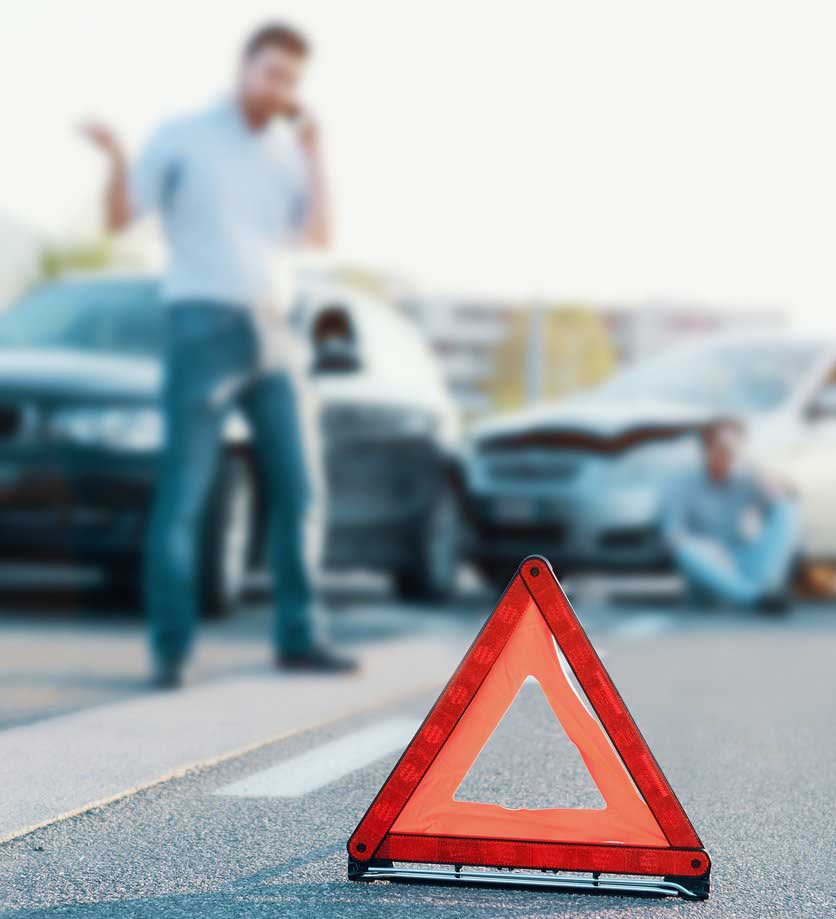 A man stands at the scene of a car accident and speaks on his cell phone