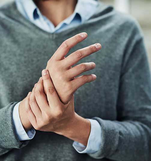 A woman massages her hand in pain