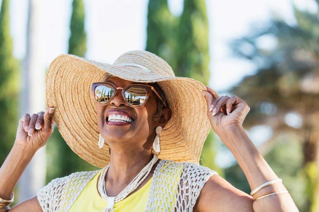 A smiling woman in a sun hat and sunglasses