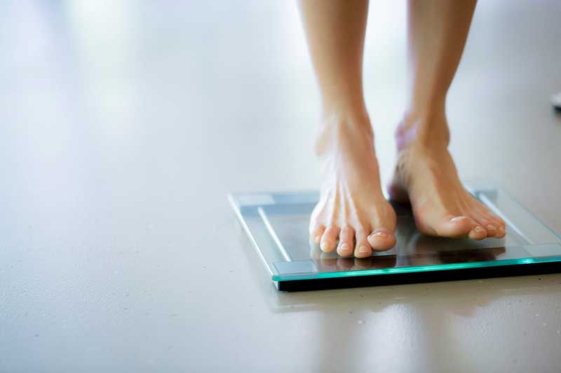 a woman stands on a modern glass scale barefoot