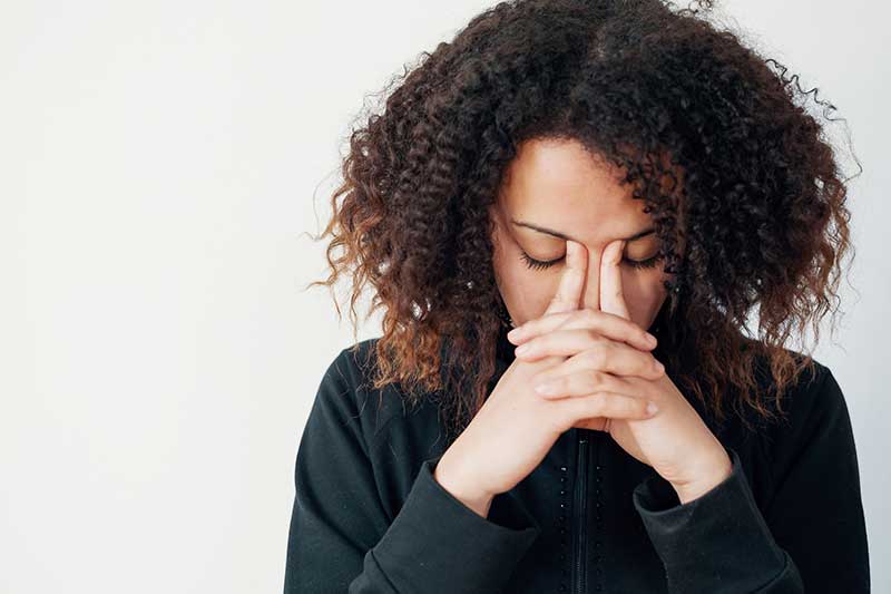 A young woman holds her forehead as if in pain