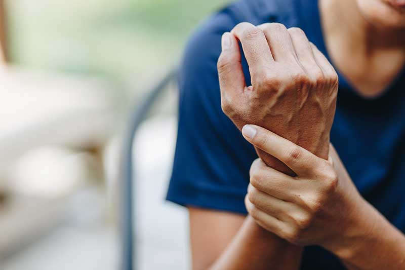 A woman holds her wrist as if in pain